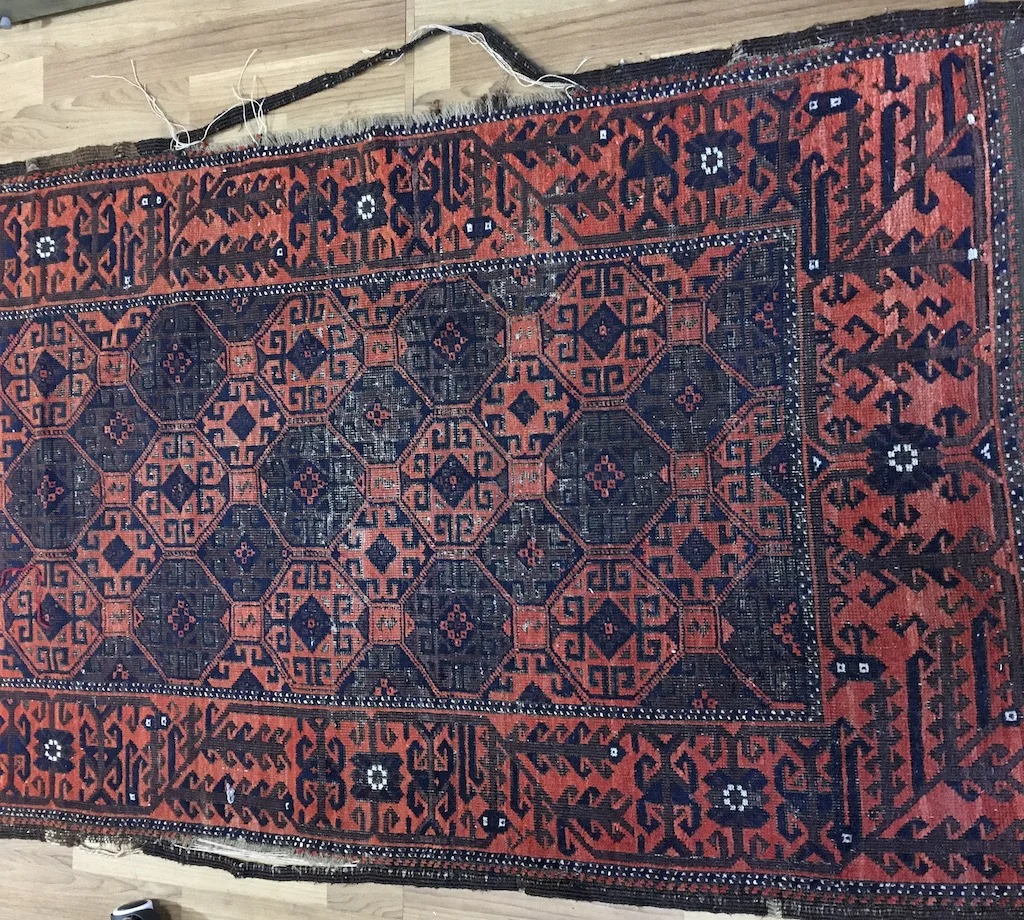 Frayed antique handmade rug with damaged edges before expert rug binding and repair at Silk Road Odyssey in San Rafael, CA.